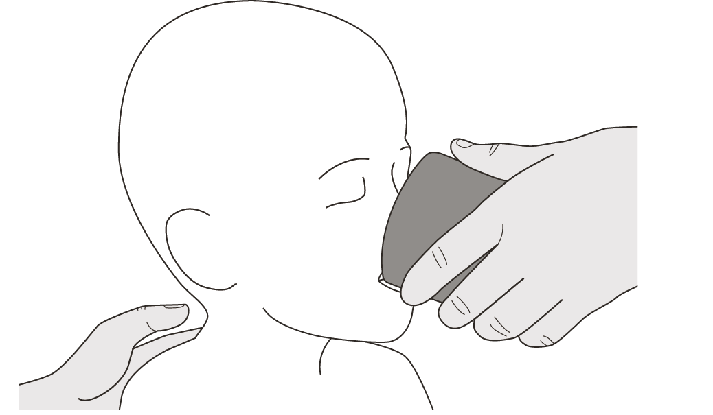A hand holding a cup to a baby's face

Description automatically generated